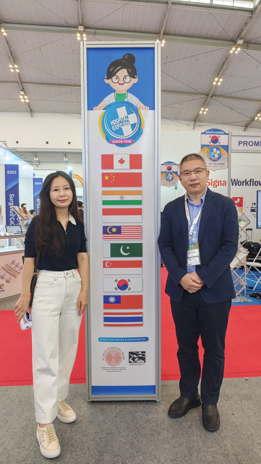 Lexaid founder and Shanghai medical expert beside a Hospital Expo stand with participating country flags